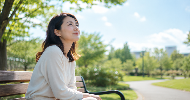 朝の静かな公園のベンチで空を眺めている。考え込んでいるというより、自分の気持ちを静かに見つめている表情